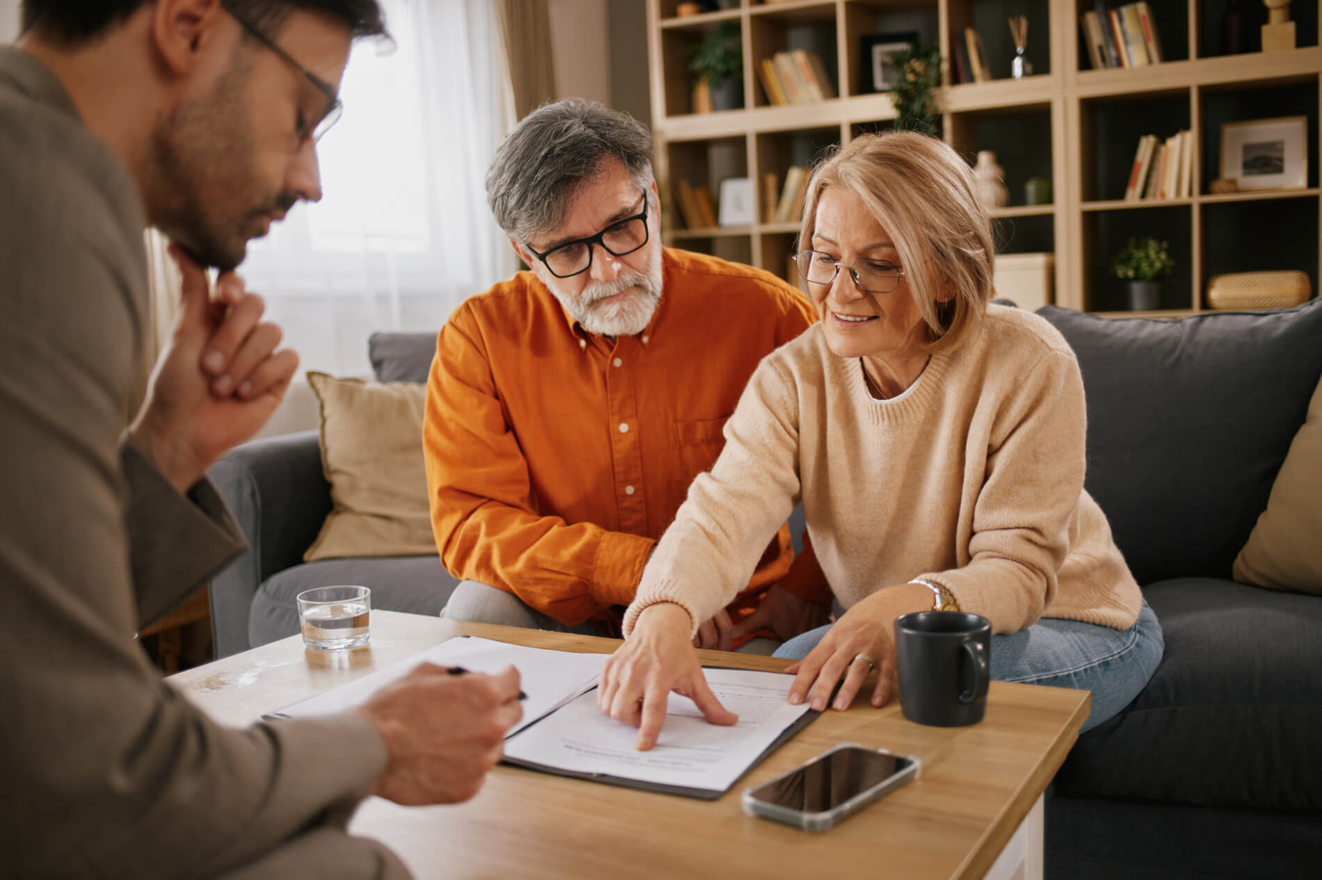 Senior couple reviewing legal document with a financial advisor in their living room